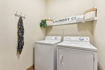 A washer and dryer in a laundry room with a shelf on the wall
